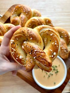 a person holding a pretzel in front of some dipping sauce