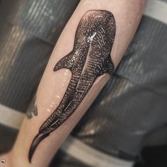 a black and white photo of a whale tattoo on the arm