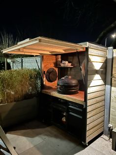 an outdoor bbq area with potted plants and lights on the roof deck at night