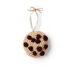 a crocheted ornament hanging from a string on a white background with brown dots