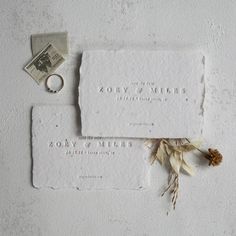 two pieces of paper with some flowers on them and a ring laying next to it