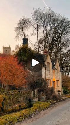 an old stone house with autumn foliage on the front and trees in the back ground