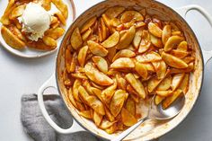 a pot filled with apples and ice cream on top of a white counter next to two plates