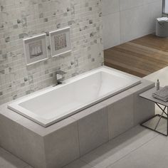 a large white bath tub sitting next to a wooden bench in a room with tiled walls