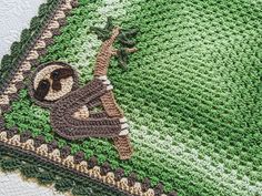 a crocheted blanket with a monkey on it's side and a green background