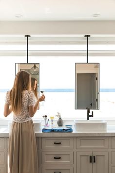 a woman standing in front of a bathroom mirror brushing her teeth with an electric toothbrush