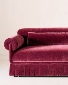 a red velvet couch with pleated cushions