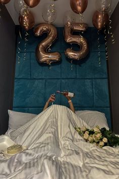 a woman laying in bed with balloons and flowers