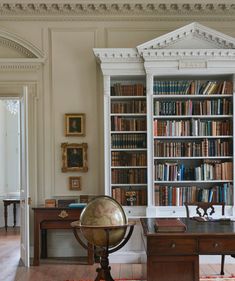 an antique globe sits in front of a bookshelf