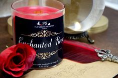 a red rose sitting next to a candle on top of a wooden table with writing