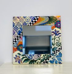 a colorful mirror sitting on top of a white table