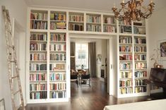 a living room filled with lots of books on top of a book shelf next to a piano