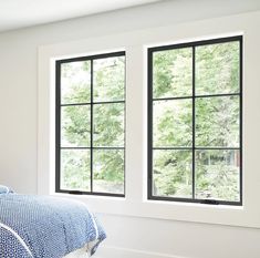 a bedroom with two windows and a blue comforter