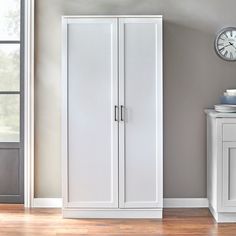 a room with a clock and two white cupboards