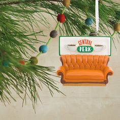 an orange couch ornament hanging from a pine tree with the words central perk on it