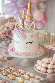 a table topped with lots of cupcakes and cakes covered in unicorn icing