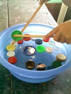 a child's hand holding a wooden stick over a blue bowl filled with paint