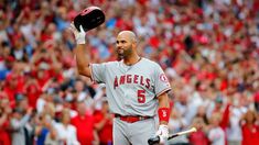 a baseball player is holding his hat and bat in the air as he walks off the field