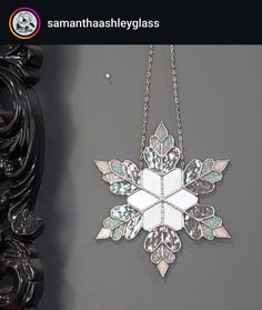 a snowflake hanging on a wall next to a black framed mirror and ornate frame