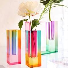 three different colored vases with flowers in them