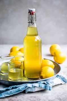 a bottle of lemonade sitting on top of a plate next to glasses and lemons