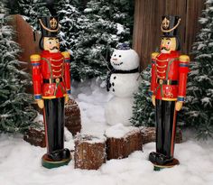 two nutcrackers and a snowman in front of some trees with snow