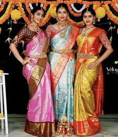 three women standing next to each other in colorful sari dresses with gold and red trims