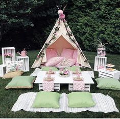 a teepee tent is set up in the grass with pillows and other items around it