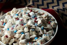 a white bowl filled with red, white and blue sprinkles next to a blanket