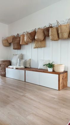 a room filled with lots of baskets hanging on the wall next to a wooden floor