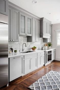 a kitchen with gray cabinets and stainless steel appliances