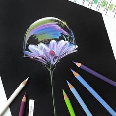 colored pencils are next to a drawing of a flower