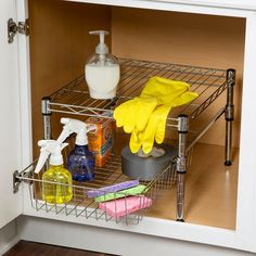 an open cabinet with cleaning supplies and sponges