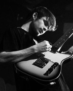 black and white photograph of a man playing an electric guitar with his hands on the neck