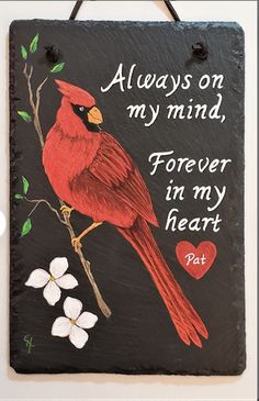 a red bird sitting on top of a black sign with words written in white writing