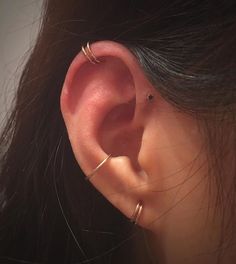 a woman's ear is shown with two thin gold rings on the end of it