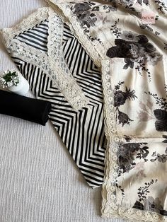 an assortment of clothing laying on top of a white bed sheet with black and white flowers