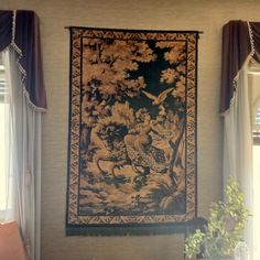 a tapestry hanging on the wall next to a potted plant in front of a window