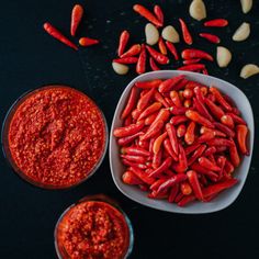 two bowls filled with red chili beans next to some peanuts and other condiments