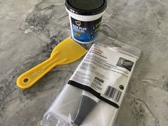 a yellow spatula next to a cup of ice cream on a marble counter top