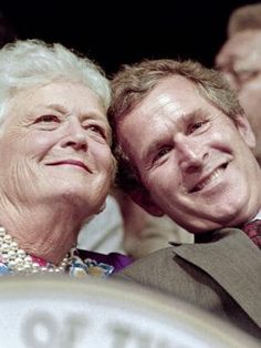 an older couple sitting next to each other in front of a large clock with people standing around it