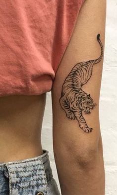 a woman with a tiger tattoo on her left arm and the other arm behind her