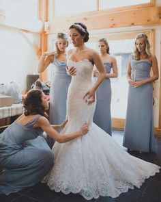 two women in dresses are helping another woman get ready to walk down the aisle for her wedding