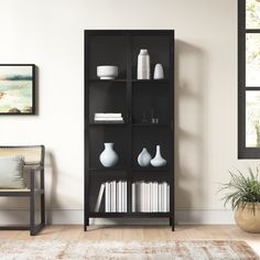 a black bookcase with books and vases on it in the corner of a room