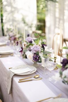 the table is set with purple and white flowers