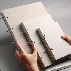 a person holding two binders on top of a book