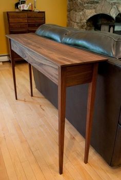 a wooden table sitting on top of a hard wood floor next to a black couch