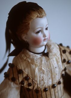 an antique doll with red hair wearing a dress