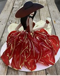 a cake that looks like a woman in a red dress and hat on a plate