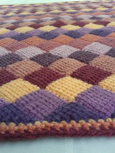 a crocheted blanket is laying on top of a bed